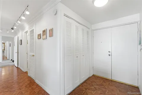 a view of a hallway with wooden floor and a bathroom