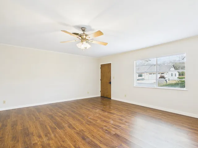 an empty room with painting on the wall and a chandelier fan