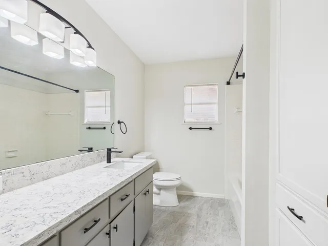 a bathroom with a granite countertop sink a toilet and a mirror
