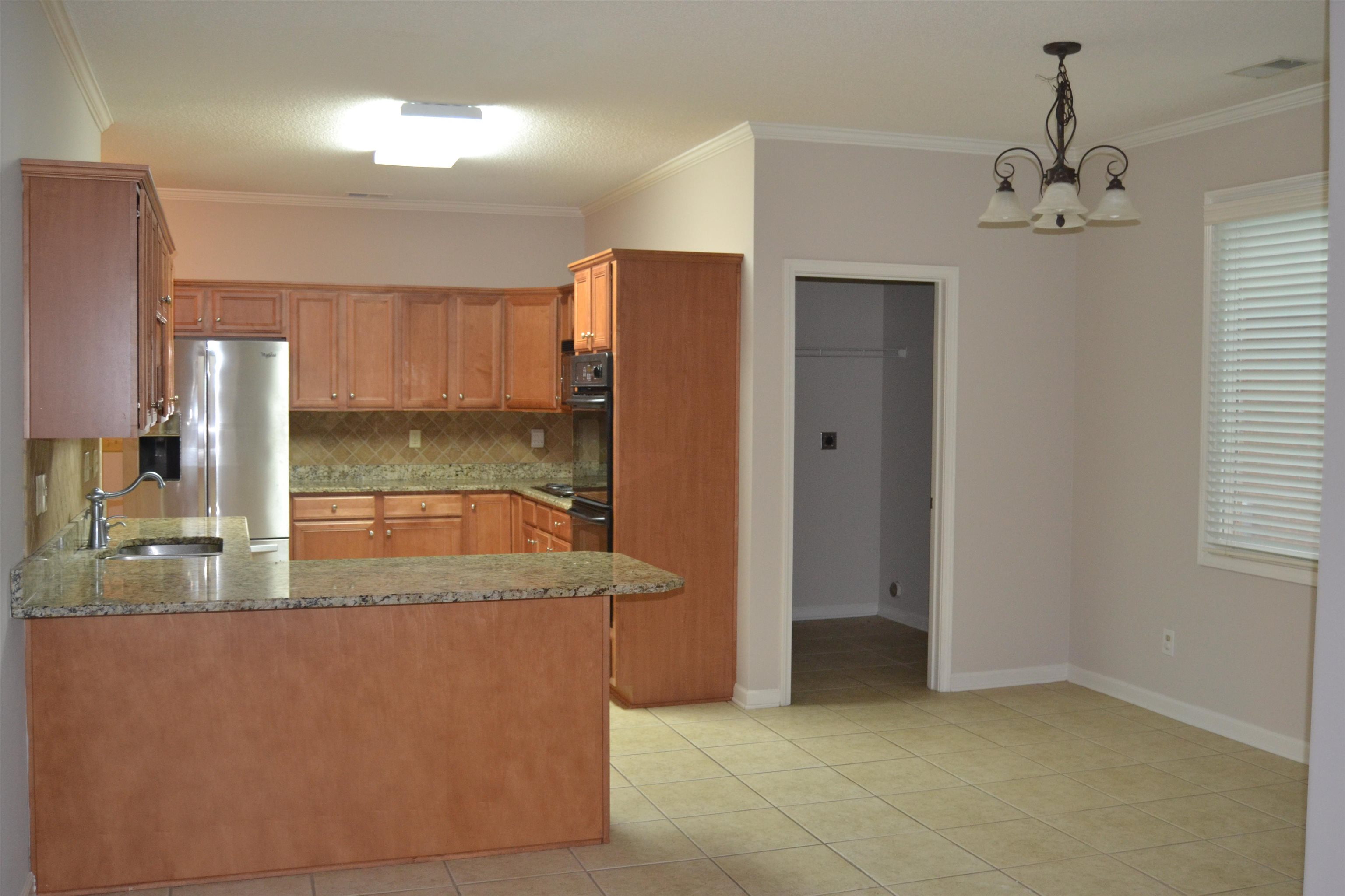 10486 Juneau Way Collierville, TN 38017 - Photo 14 of 33 Kitchen with stainless steel refrigerator with ice dispenser, backsplash, kitchen peninsula, a chandelier, and light tile patterned floors