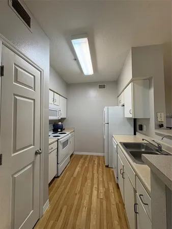 a kitchen with a sink a refrigerator and cabinets