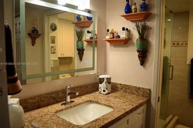 a bathroom with a granite countertop sink and a mirror