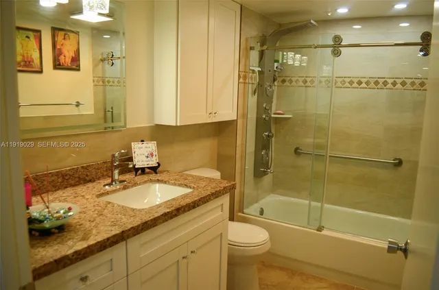 a bathroom with a granite countertop sink a toilet and shower
