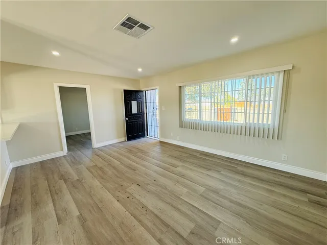 a view of an empty room with wooden floor and a window