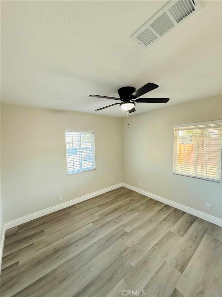 35010 Cedar Road Barstow, CA 92311 - Photo 6 of 14 an empty room with wooden floor ceiling fan and windows