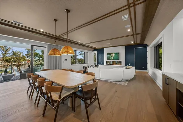 a dining room with wooden floor a chandelier a wooden table and chairs