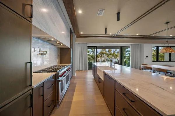 a large kitchen with stainless steel appliances a large counter top a stove and a sink