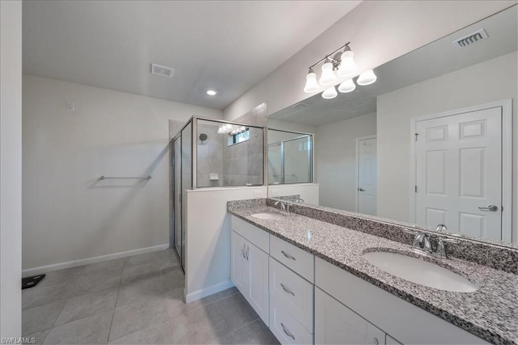 4596 Lamaida Lane Immokalee, FL 34142 - Photo 11 of 22 a bathroom with a granite countertop sink a large mirror and a shower