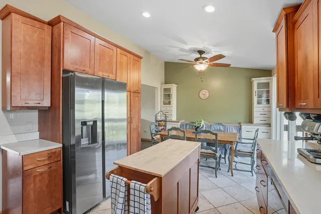 a kitchen with stainless steel appliances kitchen island granite countertop a refrigerator a stove a dining table and chairs with wooden floor