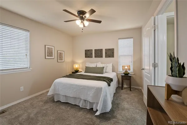 a spacious bedroom with a bed a couch and a potted plant