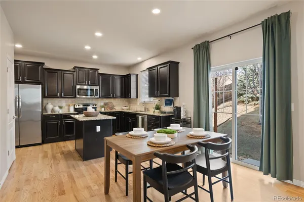 a kitchen with a refrigerator a stove a sink a dining table and chairs