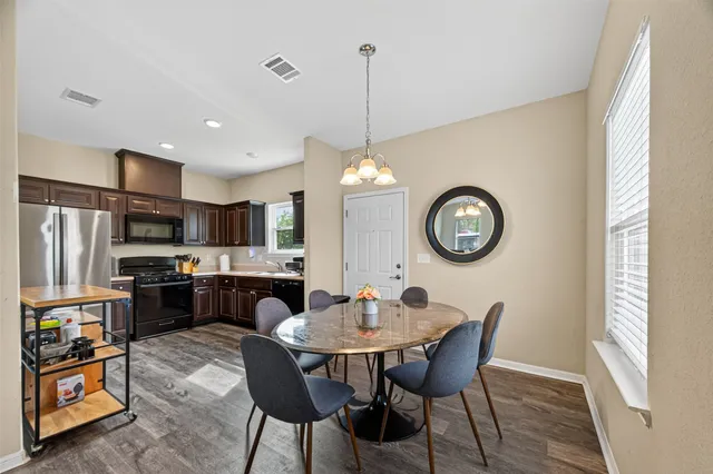 a kitchen with stainless steel appliances granite countertop a dining table chairs stove and refrigerator