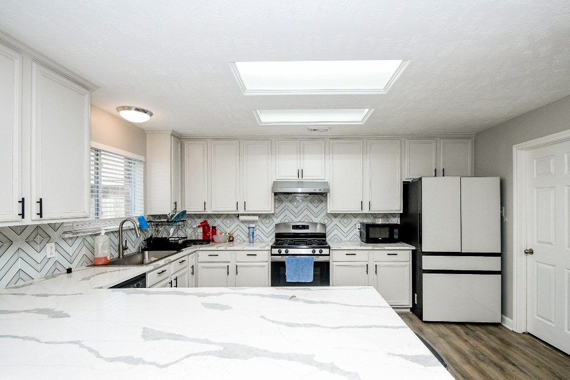 16402 Great Ridge Court Houston, TX 77083 - Photo 9 of 20 a kitchen with stainless steel appliances kitchen island granite countertop a refrigerator sink and white cabinets
