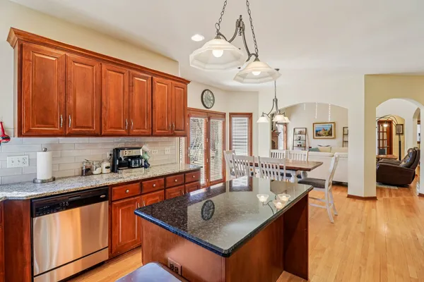 a kitchen with stainless steel appliances granite countertop a sink dishwasher stove and wooden cabinets with wooden floor