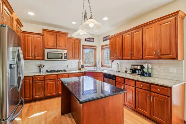 a kitchen with stainless steel appliances granite countertop a sink dishwasher stove refrigerator and cabinets with wooden floor