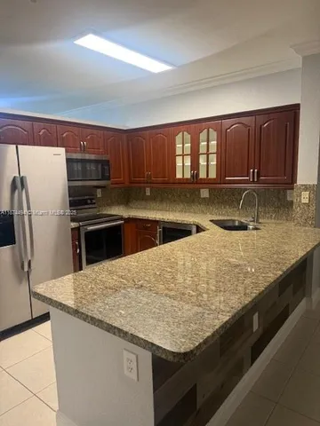 a kitchen with granite countertop a sink and a stove top oven with wooden floor
