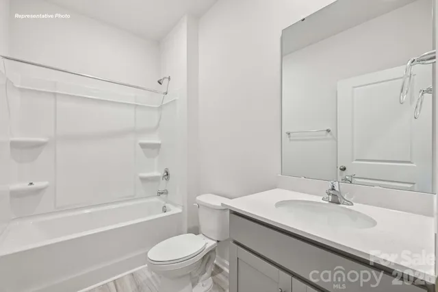 a bathroom with a granite countertop sink a toilet and shower
