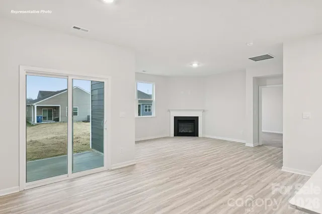 an empty room with wooden floor fireplace and windows