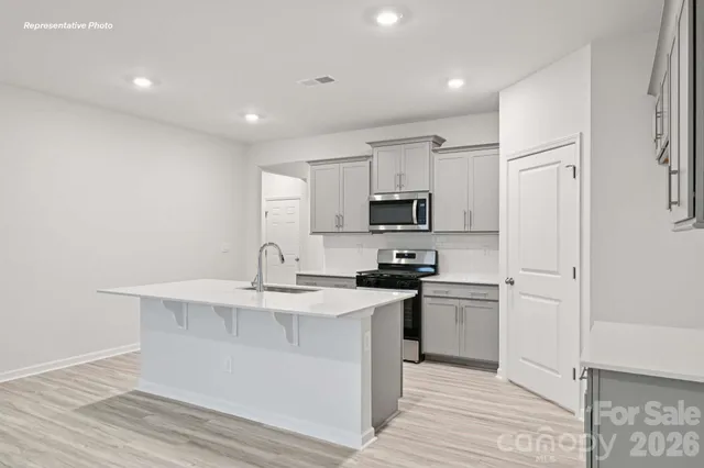 a kitchen with stainless steel appliances a white stove top oven and white cabinets