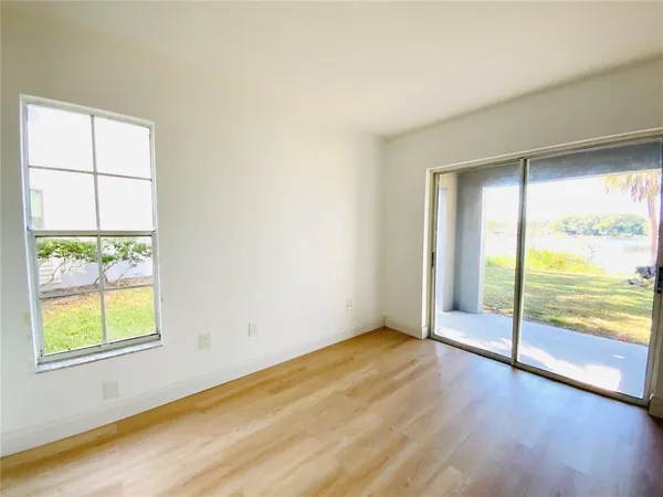 an empty room with wooden floor and windows