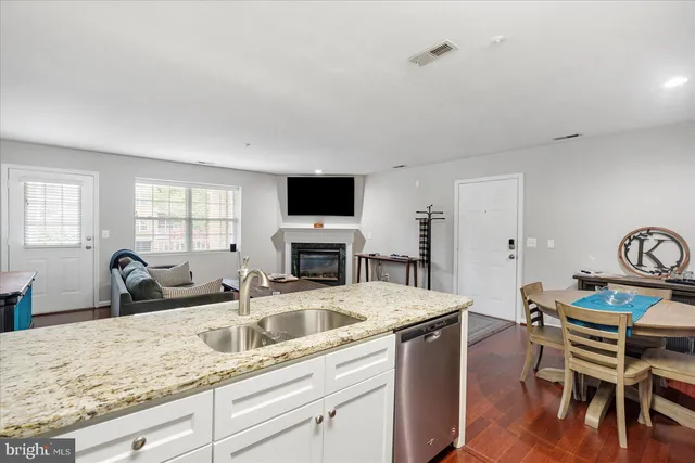 a kitchen with a stove a sink a dining table and chairs with wooden floor