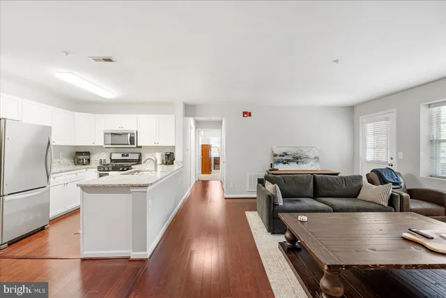 a living room with stainless steel appliances furniture and a kitchen view