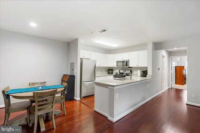 a kitchen with stainless steel appliances wooden floor and chairs