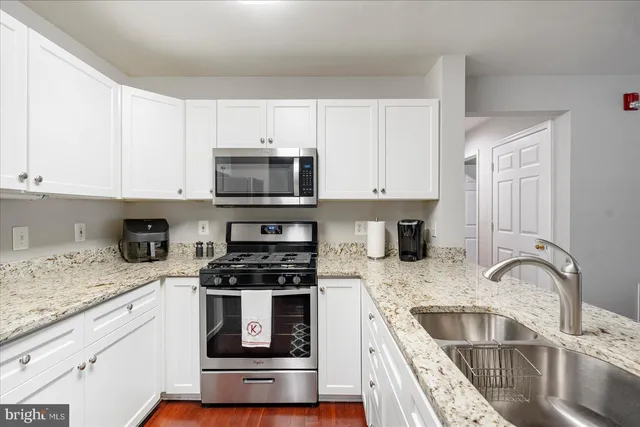 a kitchen with granite countertop a sink a stove a microwave and cabinets