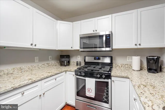 a kitchen with granite countertop white cabinets and stainless steel appliances