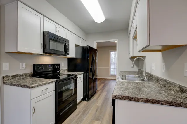a kitchen with granite countertop a sink dishwasher stove and microwave with wooden floor