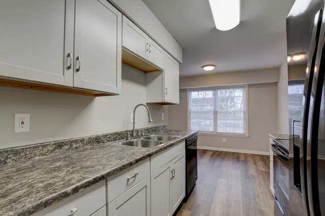 a kitchen with granite countertop a sink a stove cabinets and wooden floor