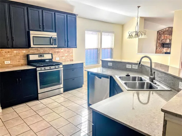 a kitchen with stainless steel appliances a sink a stove a microwave a sink a refrigerator and cabinets