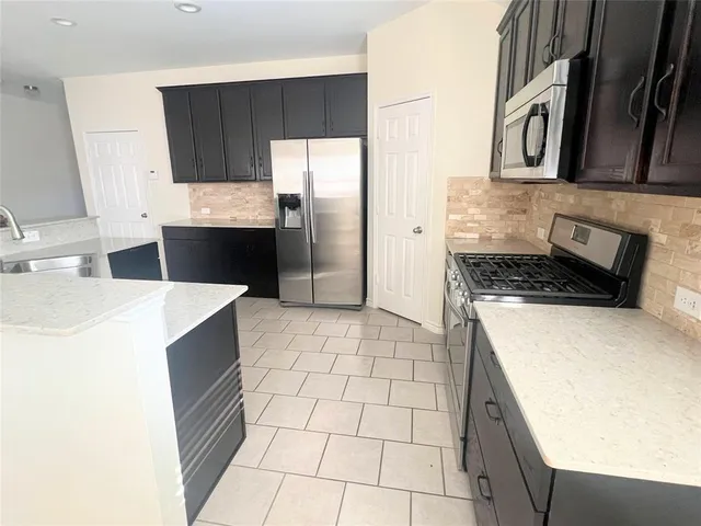 a kitchen with stainless steel appliances a refrigerator a sink a stove a microwave and cabinets