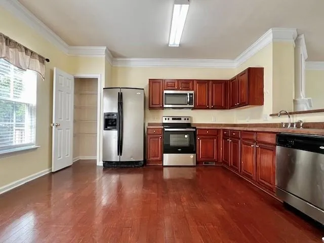 a kitchen with stainless steel appliances granite countertop a refrigerator a sink dishwasher a stove with wooden floors and cabinets