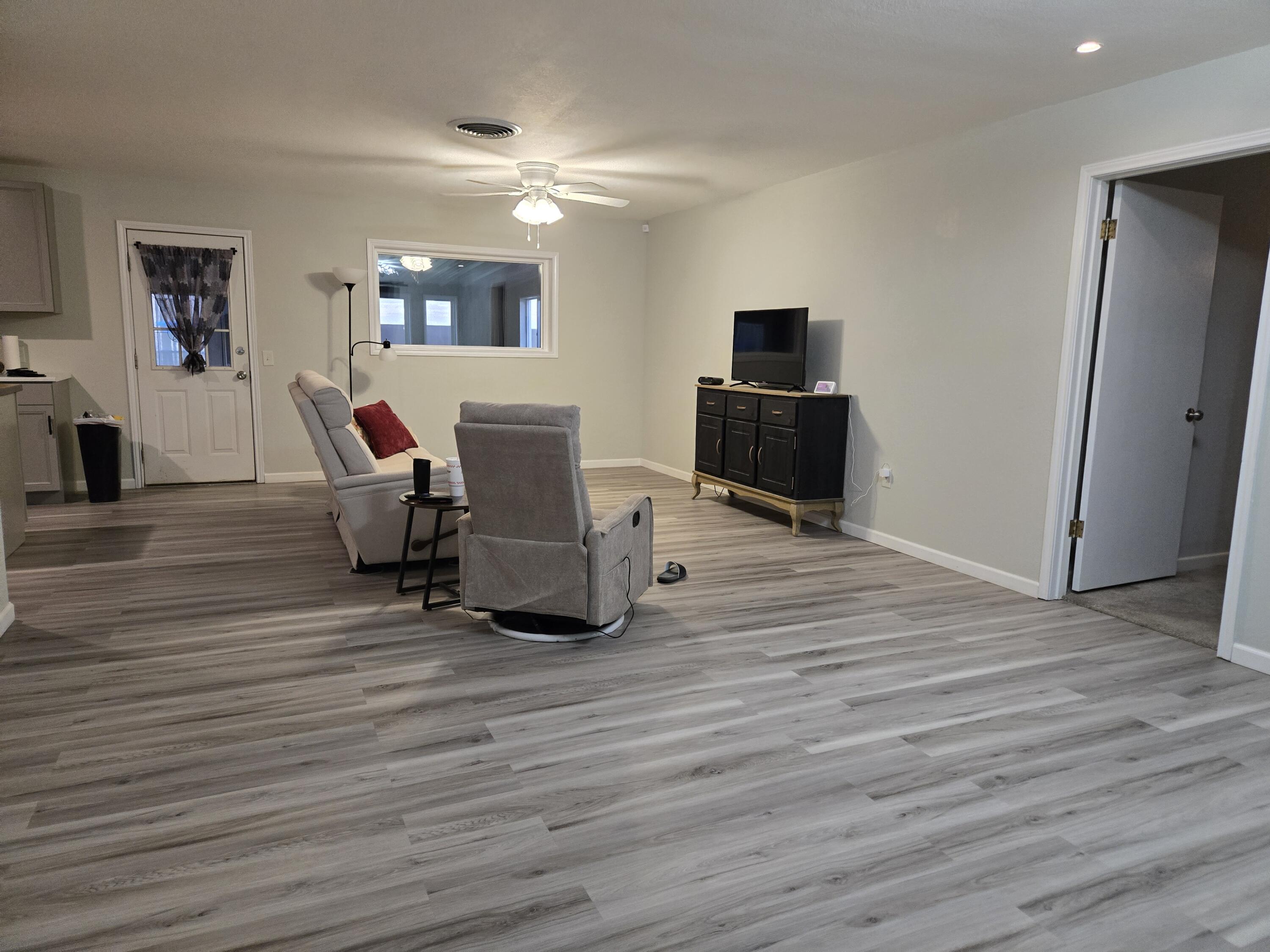 a living room with furniture flat screen tv and wooden floor