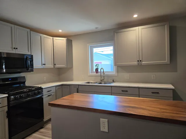 a kitchen with granite countertop a sink a stove and cabinets
