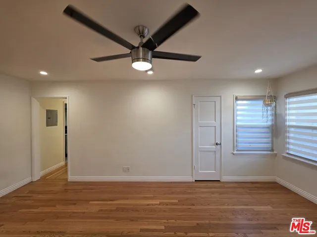 an empty room with wooden floor fan and windows