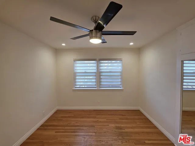 an empty room with wooden floor ceiling fan and windows