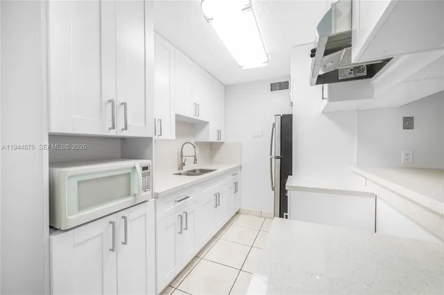 a kitchen with granite countertop white cabinets and stainless steel appliances