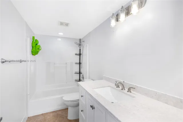 a bathroom with a granite countertop sink a toilet a shower and a mirror