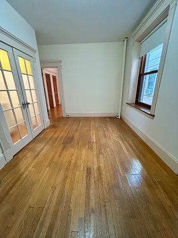 a view of an empty room and wooden floor and windows
