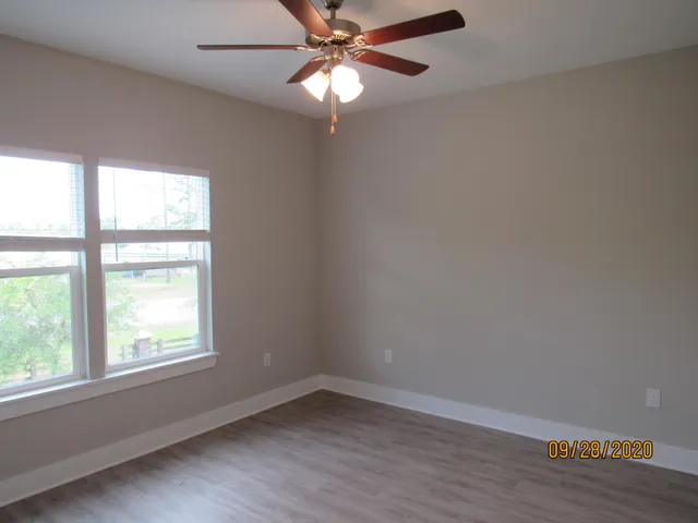 an empty room with wooden floor and a ceiling fan