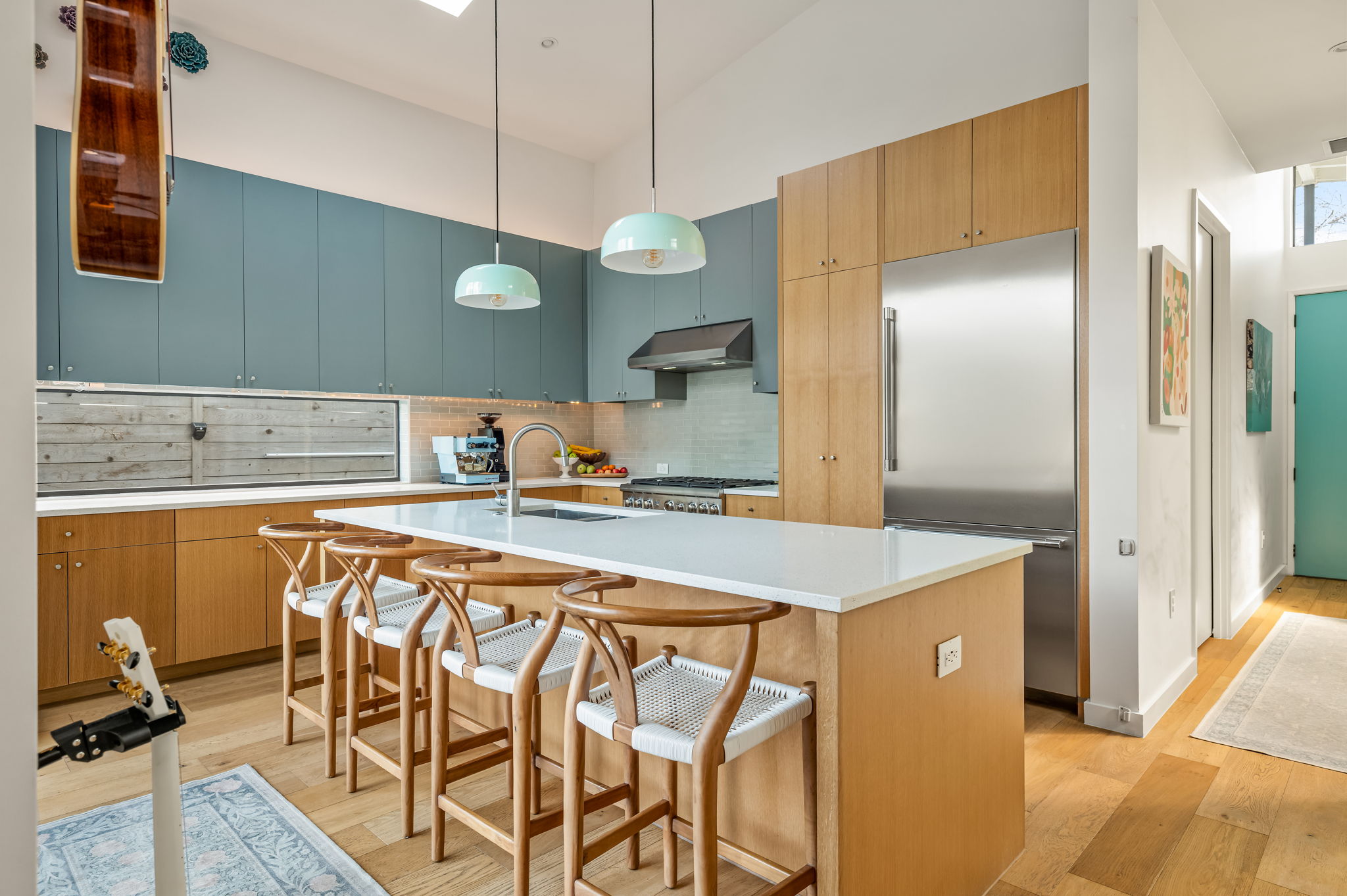 1811 Collier Street Austin, TX 78704 - Photo 5 of 40 Kitchen with a breakfast bar, stainless steel appliances, light wood-type flooring, backsplash, and a high ceiling