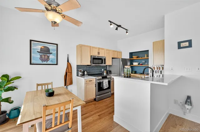a kitchen with stainless steel appliances granite countertop a refrigerator a stove top oven a sink dishwasher and white cabinets with wooden floor