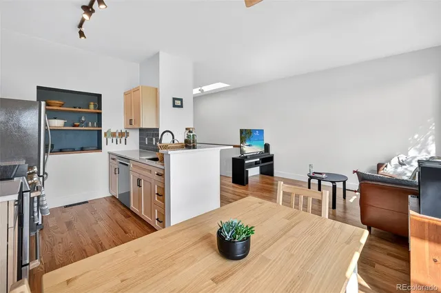 a living room with furniture a dining table wooden floor and a fireplace