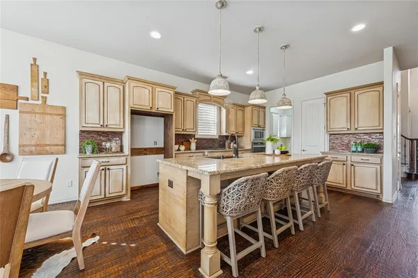 a kitchen with stainless steel appliances granite countertop a stove top oven a refrigerator a sink and white cabinets with wooden floor