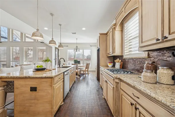 a kitchen with stainless steel appliances granite countertop a sink a stove and a wooden floors