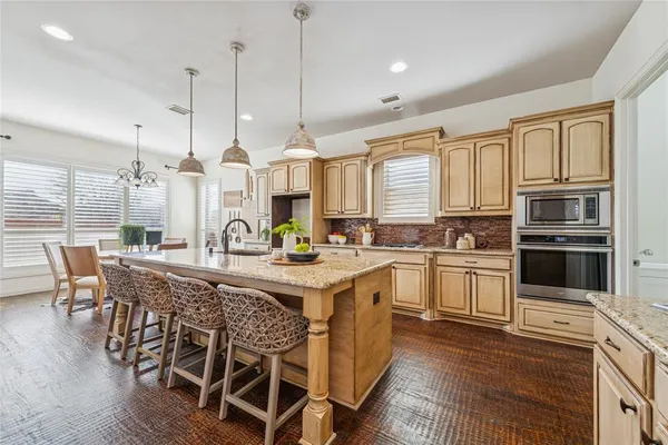 a kitchen with stainless steel appliances granite countertop a stove a sink dishwasher a dining table and chairs with wooden floor
