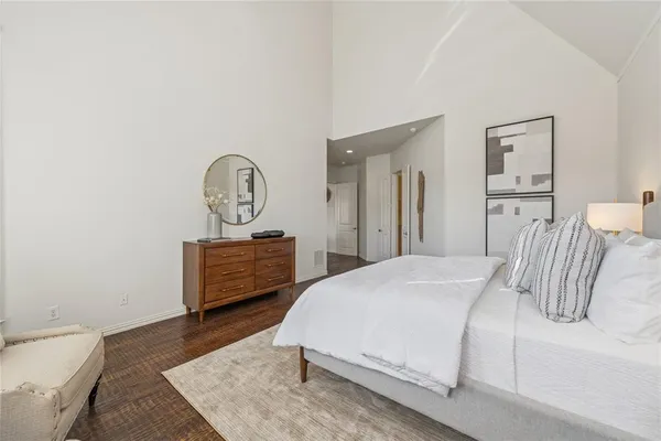 a bedroom with a bed a mirror and a table with wooden floor