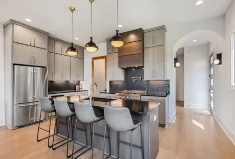 a kitchen with stainless steel appliances granite countertop a sink a stove a refrigerator cabinets and chairs